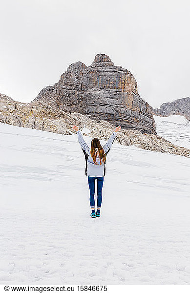young millennial girl enjoys the views of the Alps standing on glacier