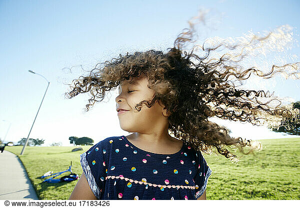 Young mixed race girl aged 4 outdoors  curly hair fanning out