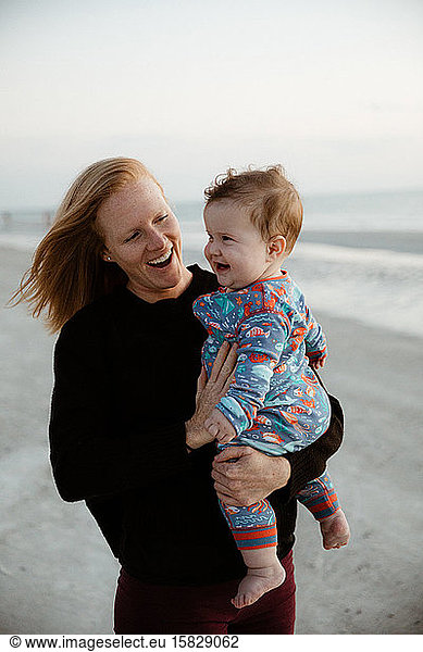 young mother and healthy chubby boy child smile during beach walk