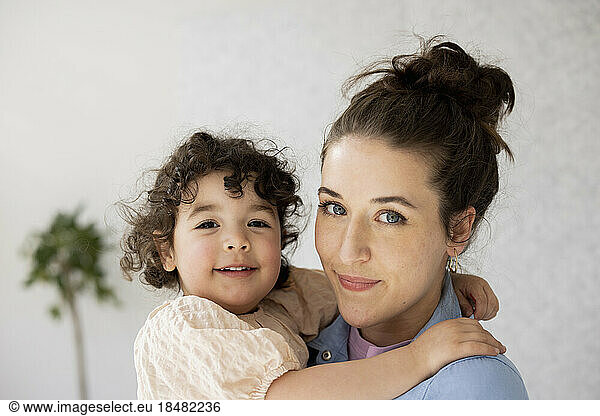 Young mother holding daughter looking at camera