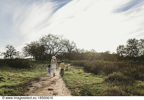 Young mother  son  and daughter holding hands while walking away