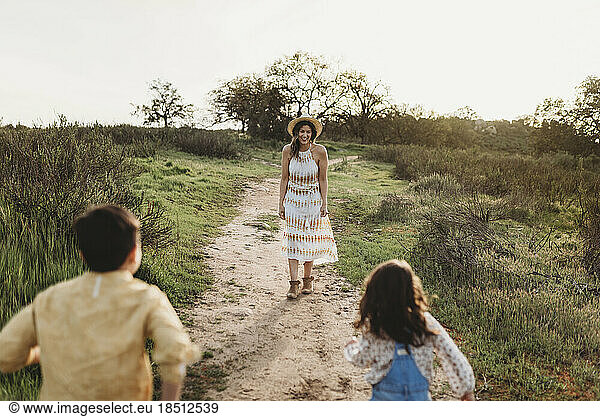 Young mother standing in field waiting for children to run to her
