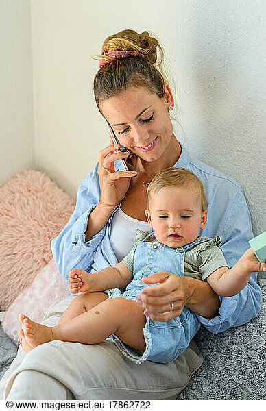 young mother talking on phone while toddler sitting