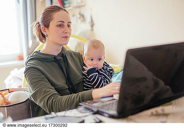 Young mother working from home together with her baby