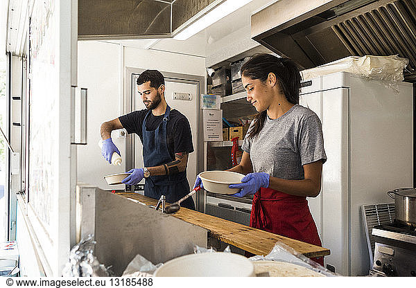 Young multi-ethnic male and female colleagues preparing food in food truck