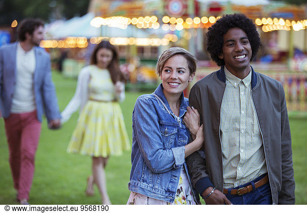 Young multiracial couple smiling while walking in amusement park