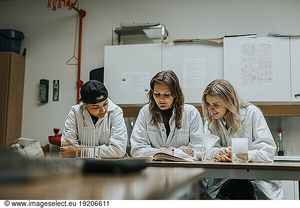 Young multiracial students studying at desk in laboratory
