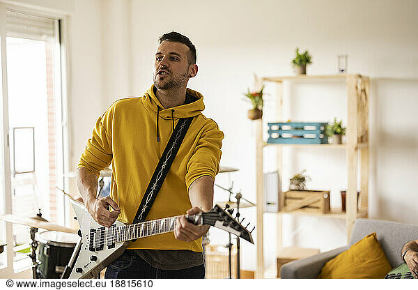 Young musician playing electric guitar at home