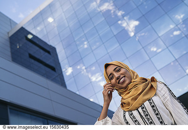 Young muslim woman wearing yellow hijab  building with glass facade in the background