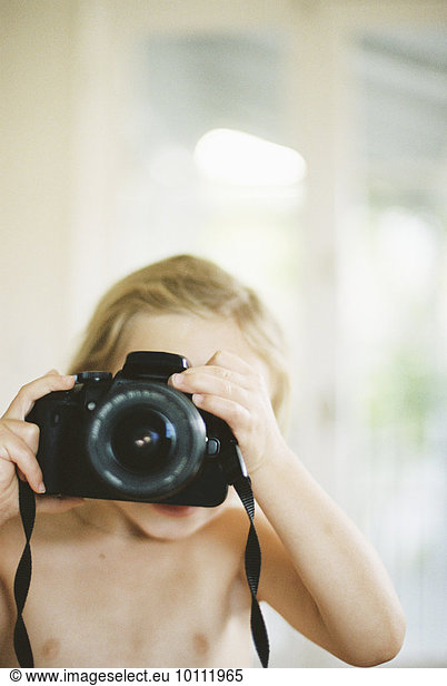 Young nude girl taking a picture with a camera.