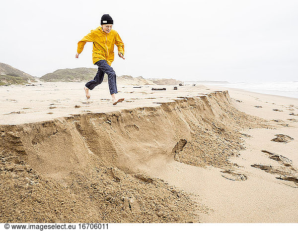 Young person running toward sandy ledge at California beach
