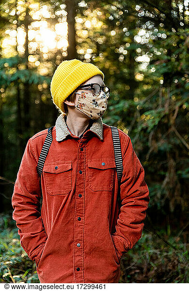 Young person standing in forest wearing mask during global pandemic