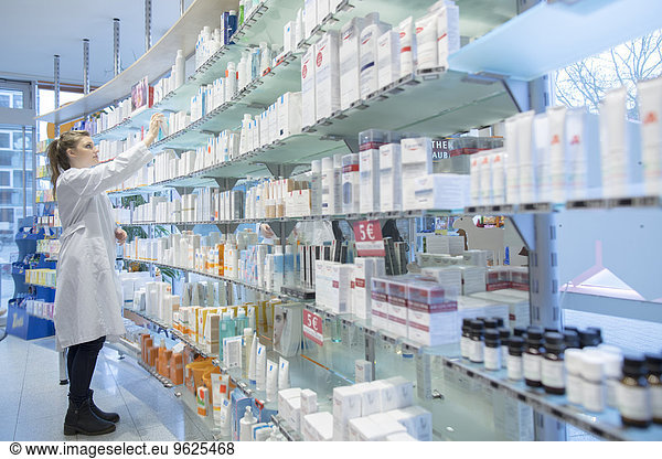 Young pharmacist in pharmacy choosing medication