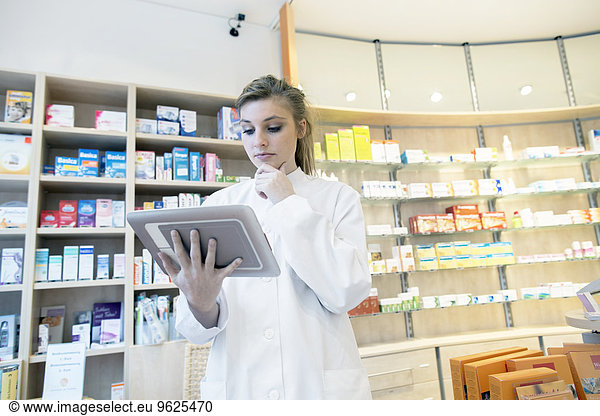 Young pharmacist in pharmacy  using digital tablet