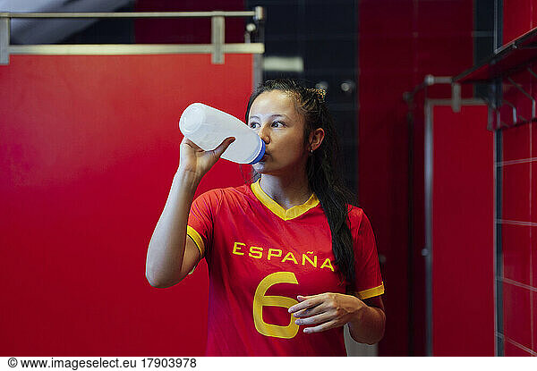 Young player drinking water in locker room