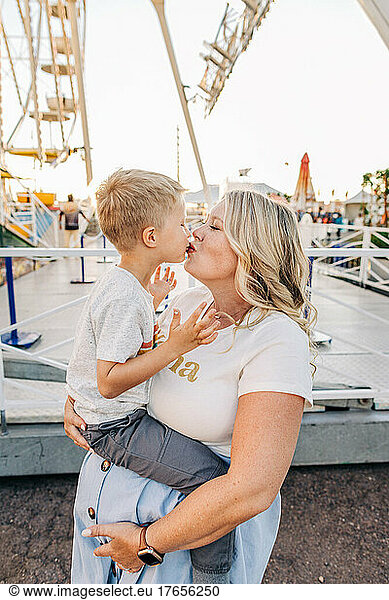 Young pregnant Caucasian mother kisses son at state fair