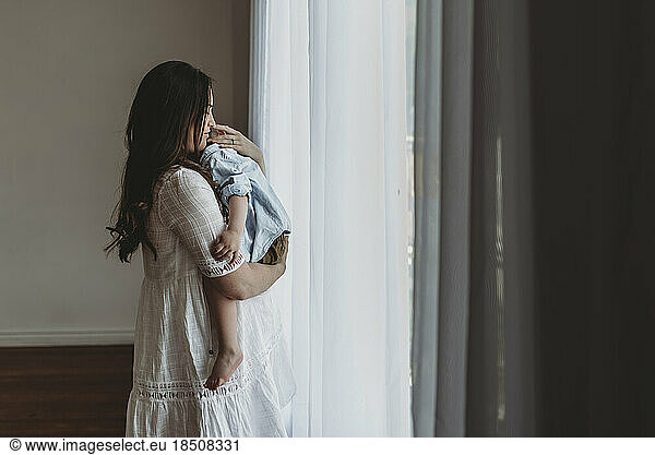 Young pregnant mother cuddling with young son in natural light studio