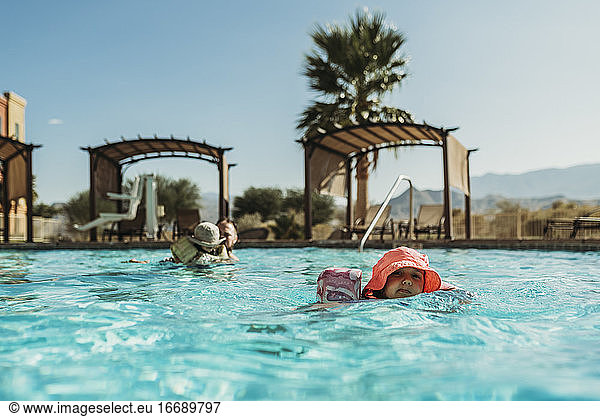 Young preschool age girl swimming in pool on vacation in Palm Springs