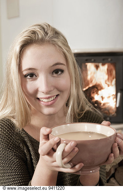 Young pretty blond teenage girl drinking coffee fire