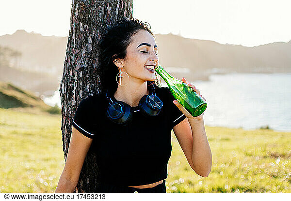 Young pretty caucasian girl drinking beer and listening to music