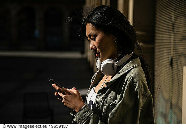Young pretty confident woman texting and wearing headphones.