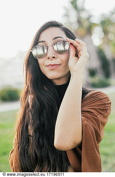 Young pretty woman holding her sunglasses and looking at the camera