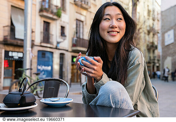 Young relaxed woman having a cup of tea in a bar terrace.