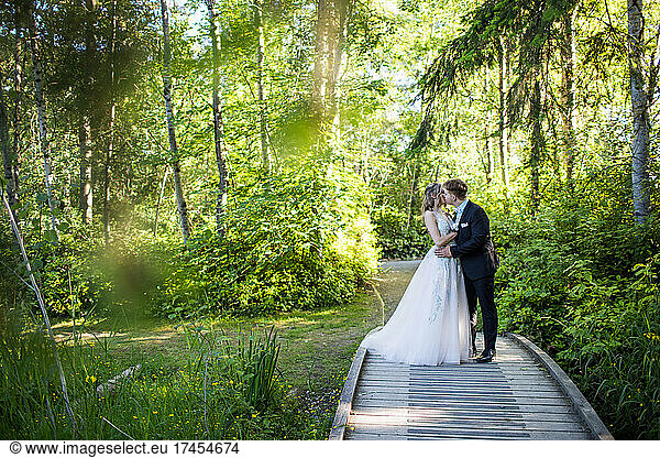 Young romantic couple kiss in forest setting.
