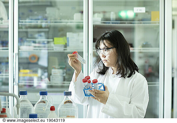 young scientist female controlling a tube of a rack