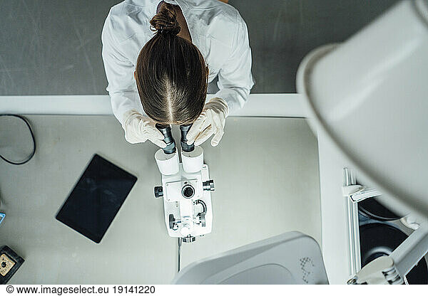 Young scientist working with microscope in laboratory