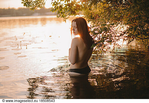 Young sensual woman in lake at sunset