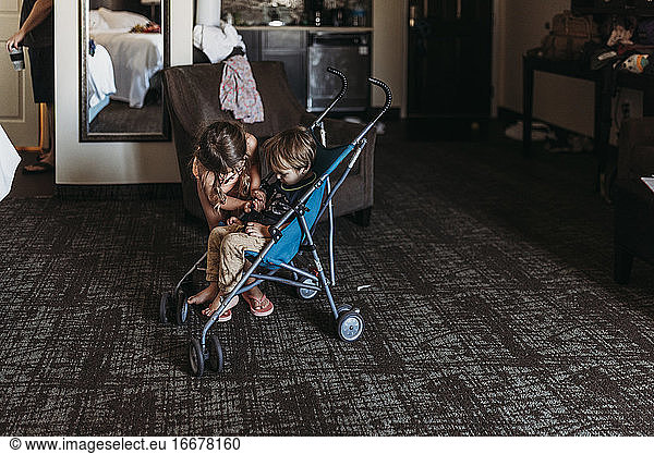 Young siblings playing in stroller in hotel room in Palm Springs