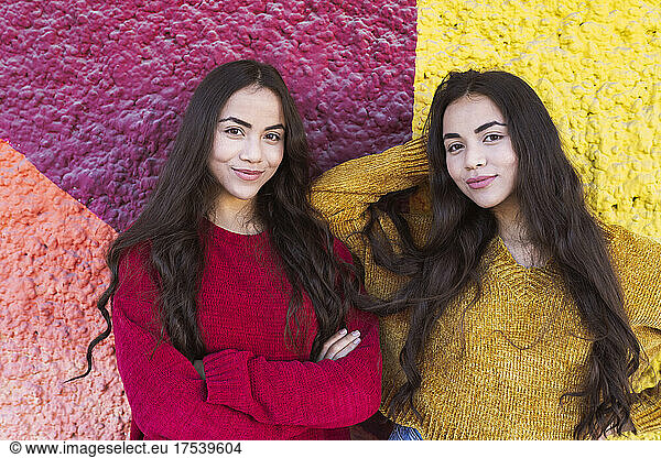 Young sisters smiling in front of colorful wall