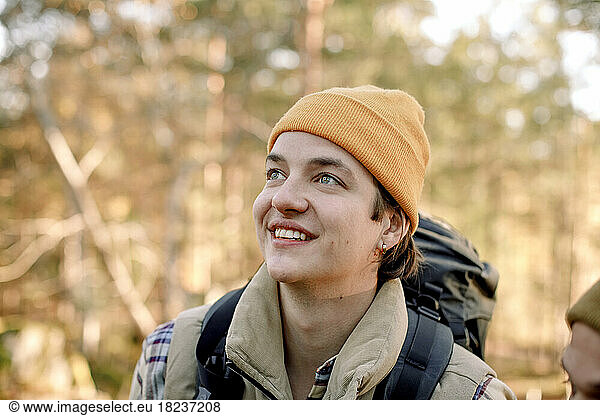 Young smiling man wearing knit hat looking away during hiking