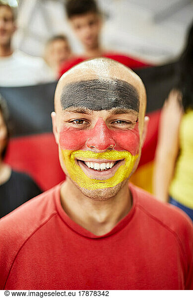 Young smiling man with German Flag painted of face at stadium