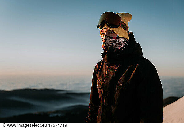 Young Snowboarder wearing snowsuit goggle and buff in the mountains