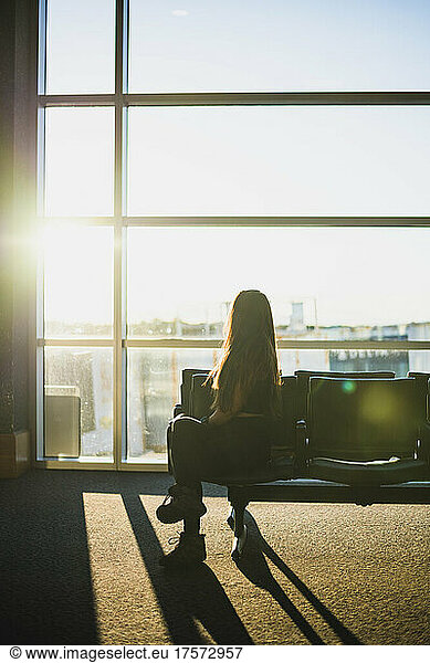 Young Solo Woman waiting at empty airport during golden hour