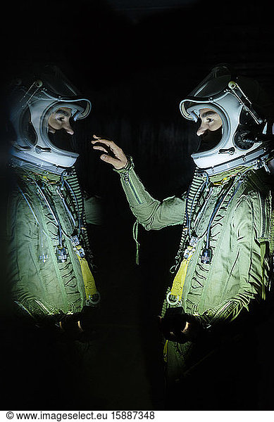 Young spaceman touching his reflection in the dark