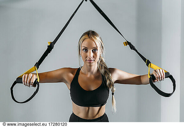 Young sports woman preparing for suspension training in gym