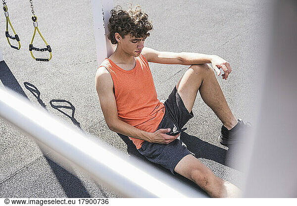 Young sportsman using smart phone on sunny day