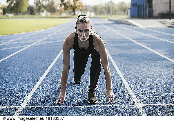 Young sportswoman at starting line of track