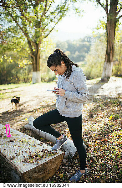 Young sportswoman using smartphone in the park