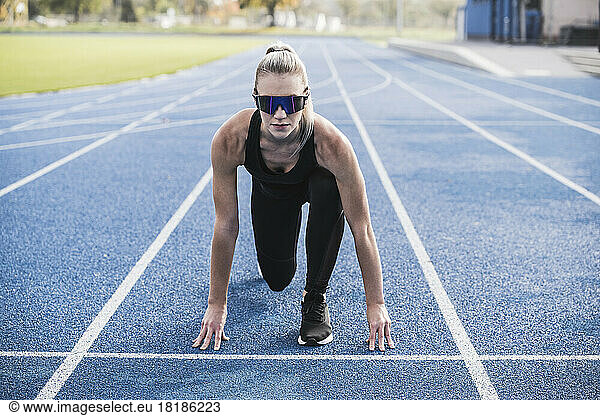 Young sportswoman wearing smart glasses at starting line of track