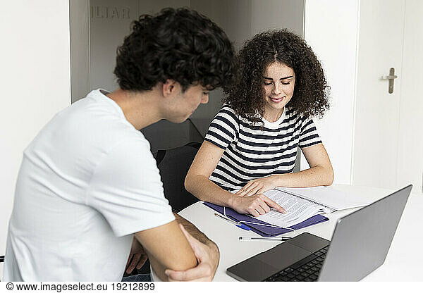 Young student explaining friend at table in university