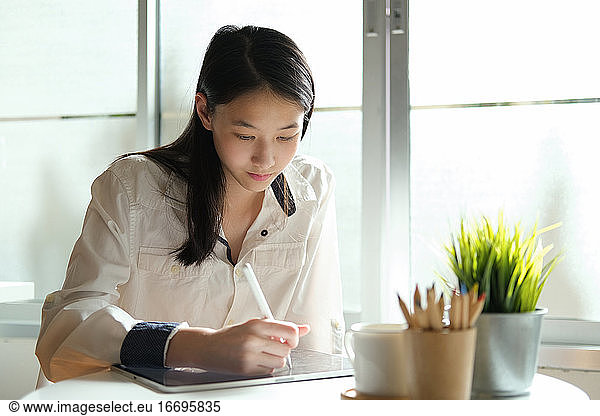 Young student girl using degital pen write on tablet.