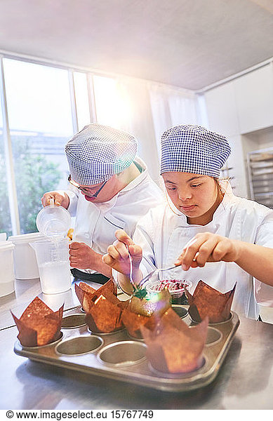 Young students with Down Syndrome baking muffins in kitchen