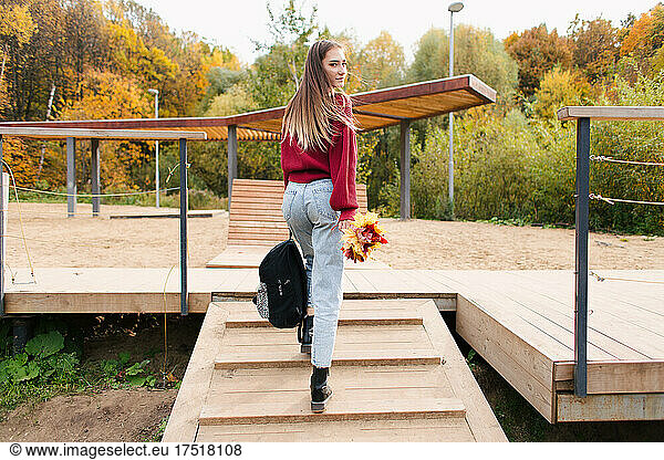 Young stylish girl walking in autumn park back view