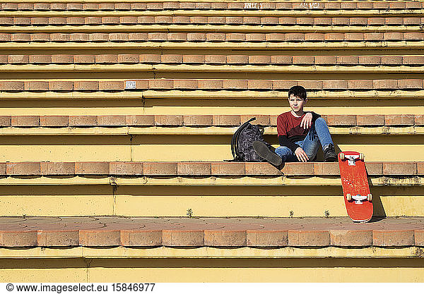 Young teen sitting on stairs outdoors  looking away in sunny day