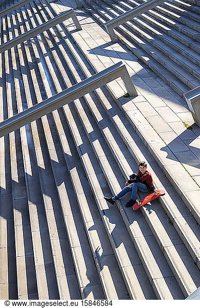 Young teen sitting on stairs outdoors  looking camera in sunny day