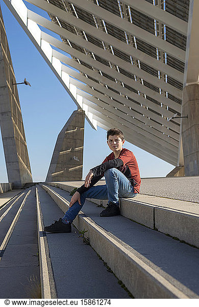 Young teen sitting on stairs outdoors  looking camera in sunny day